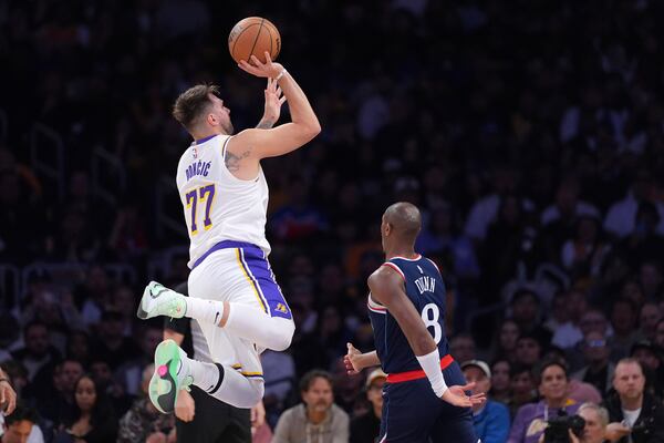 Los Angeles Lakers guard Luka Doncic, left, shoots as Los Angeles Clippers guard Kris Dunn defends during the first half of an NBA basketball game Sunday, March 2, 2025, in Los Angeles. (AP Photo/Mark J. Terrill)