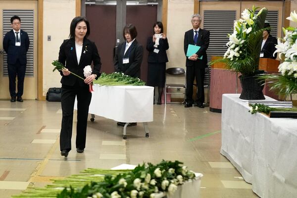 Akiko Ikuina, Parliamentary Vice-Minister for Foreign Affairs, offer a flower on behalf of the government during a memorial ceremony for the Sado Island Gold Mine in Sado, Niigata prefecture, Japan, Sunday, Nov. 24, 2024. (AP Photo/Eugene Hoshiko)