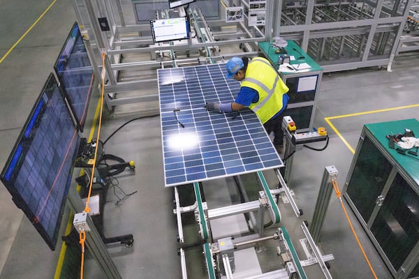 A worker makes a visual inspection of one of the solar panels as it moves through the automated assembly line at the Qcells module production facility in Cartersville on Tuesday, April 2, 2024. (AJC File)