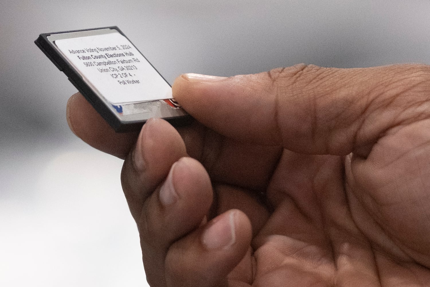 A worker holds a memory card while loading advance voting results at the Fulton County election hub in Fairburn on Tuesday, Nov. 5, 2024.   Ben Gray for the Atlanta Journal-Constitution