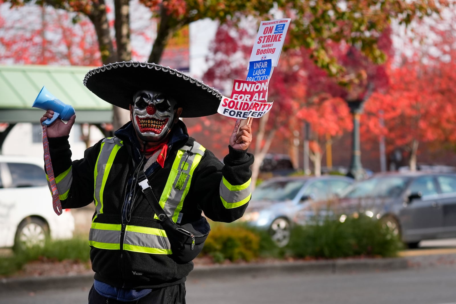 Boeing mechanic Eugenio, who preferred not to give a last name, sounds a bullhorn while holding a sign as employees gather to vote on a new contract offer from the company, Wednesday, Oct. 23, 2024, in Everett, Wash. (AP Photo/Lindsey Wasson)