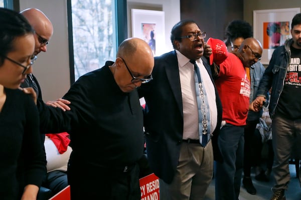 Rev. Timothy McDonald III (center), senior pastor of First Iconium Baptist Church, standing next to former state Senator Vincent Fort, leads protesters in prayer as they occupy the reception area of the mayor's office.  The Housing Justice League held a rally at City Hall and a sit-in at the Mayor's Office on December 16, 2019. The protesters want Atlanta Mayor Keisha Lance Bottoms to let Peoplestown residents in the city stay in their homes and not be displaced by eminent domain to build a park and retention pond.  Bob Andres / bandres@ajc.com