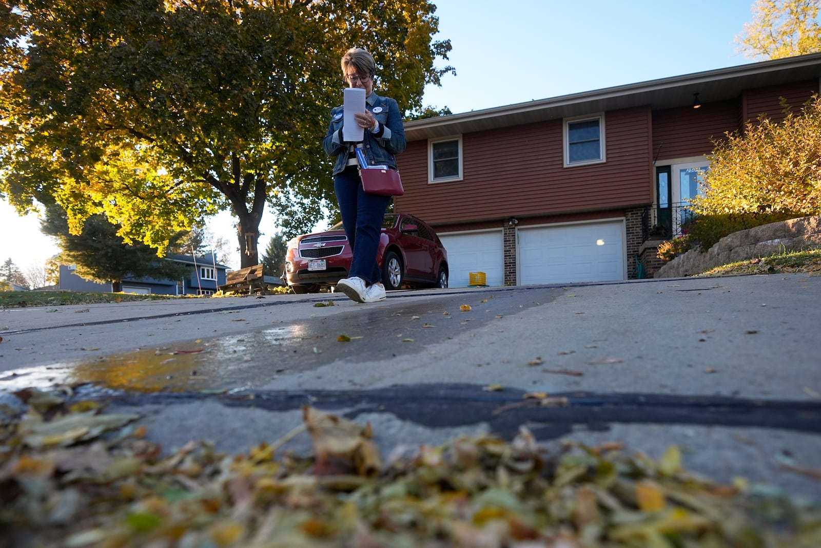 Kathy Moran canvases houses Wednesday, Oct. 23, 2024, in Cross Plains, Wis. (AP Photo/Morry Gash)