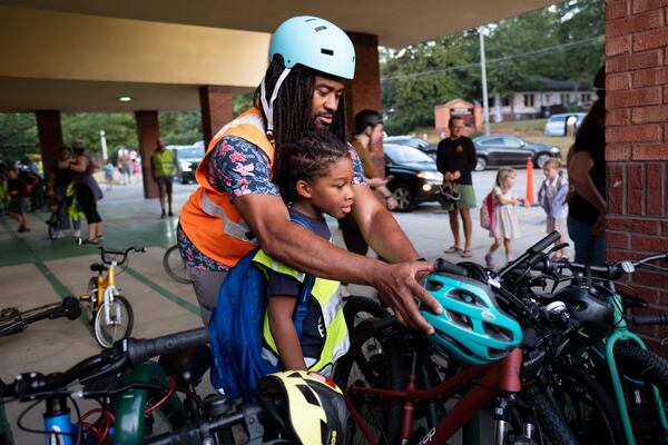 David Franklin helps hang is son Dawson’s helmet after the pair rode with the weekly Parkside Elementary School “bike bus” Friday, Sept. 20, 2024, in Atlanta. Ben Gray for the Atlanta Journal-Constitution