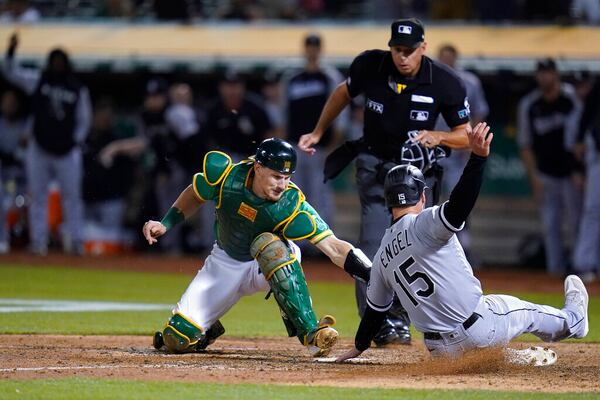 Oakland Athletics catcher Sean Murphy, left, tries to tag Chicago White Sox's Adam Engel (15), who scored the tying run during the ninth inning of a baseball game in Oakland, Calif., Sept. 9, 2022. The Atlanta Braves acquired catcher Murphy from the Oakland Athletics as part of a three-team deal on Monday, Dec. 12, 2022, that also sent catcher William Contreras to the Milwaukee Brewers. (AP Photo/Godofredo A. Vásquez, File)