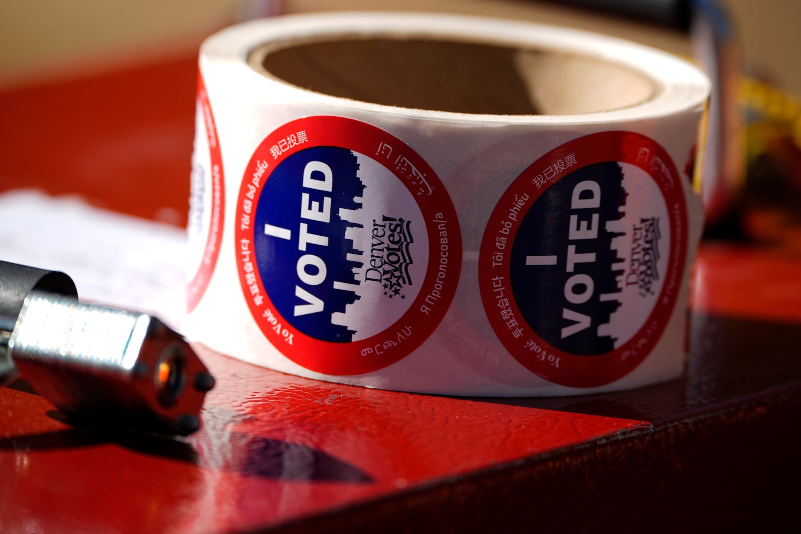 Stickers for voters sit in a roll on a ballot box at a voting drop-off location Friday, Oct. 25, 2024, in Washington Park in Denver. (AP Photo/David Zalubowski)