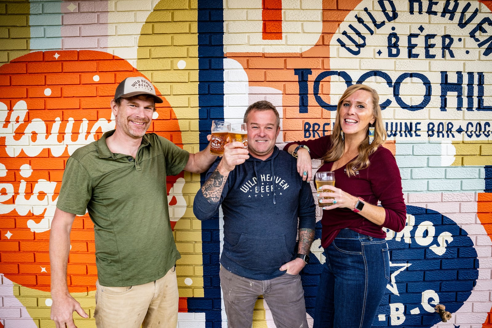 Wild Heaven owners Nick Purdy, Eric Johnson and Sarah Young pose in front of a mural outside their new Toco Hill location.