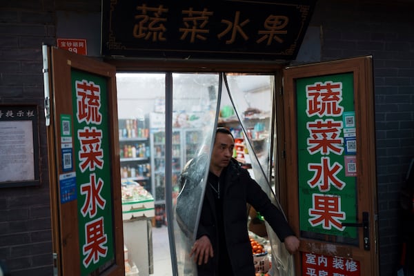 A resident walks out from a local convenience store in downtown Beijing, China, Saturday, March 8, 2025. (AP Photo/Vincent Thian)