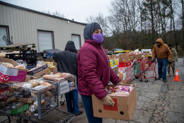 Volunteer Ida  Boswell loads a box of food in the trunk of a family in need during at the Hearts to Nourish Hope mobile food pantry in Riverdale last month. Experts say that the foreclosure moratorium might have played an outsized role in keeping bankruptcy filings low in Georgia. (Alyssa Pointer / Alyssa.Pointer@ajc.com)