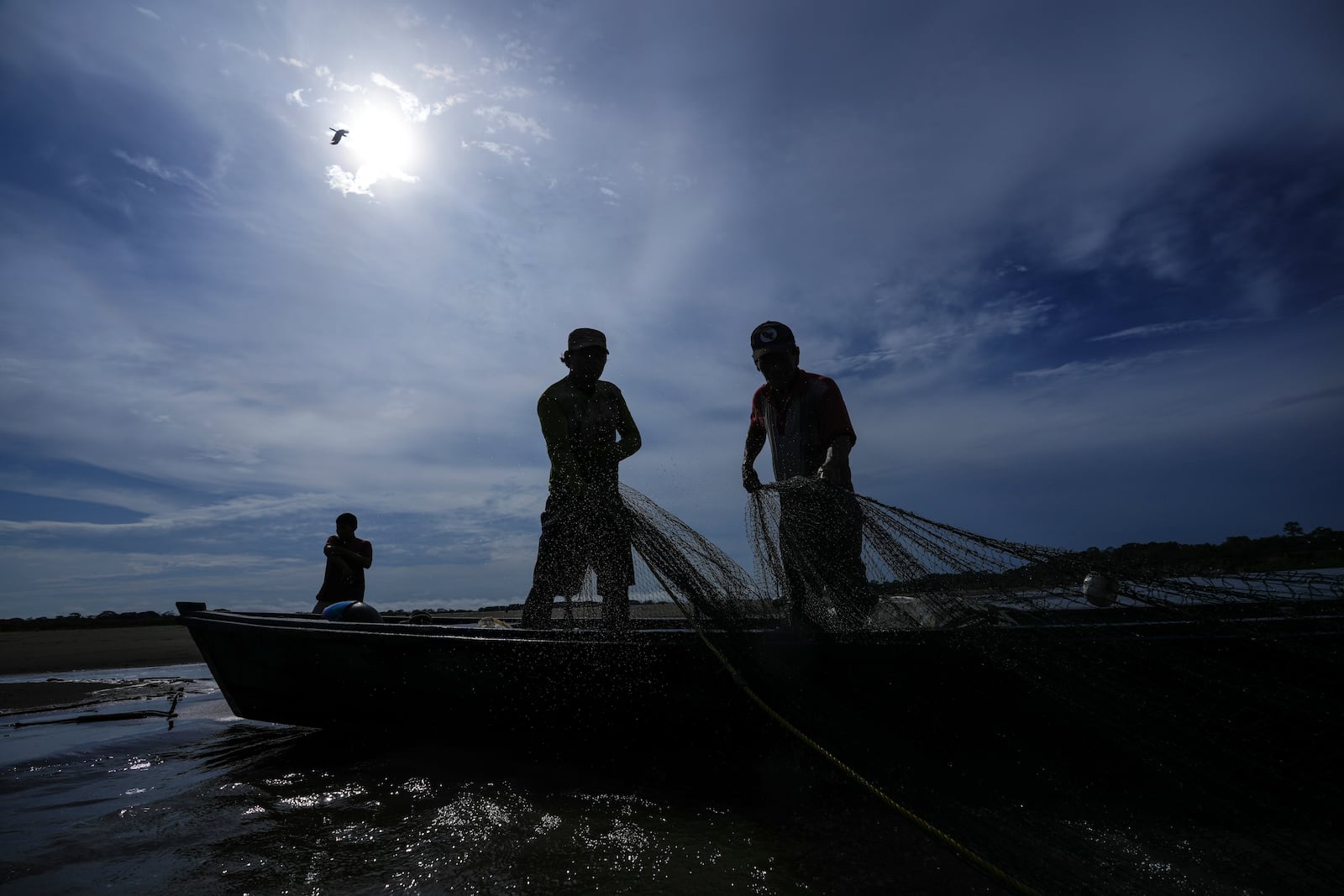 Men look for fish in the Amazon River amid a drought on the outskirts of Leticia, Colombia, Monday, Oct. 21, 2024. (AP Photo/Ivan Valencia)