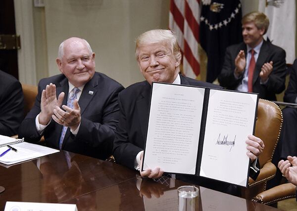 President Donald Trump signs the Executive Order promoting Agriculture and Rural Prosperity in America as Agriculture Secretary Sonny Perdue looks on during a roundtable with farmers on Tuesday, April 25, 2017, in the Roosevelt Room of the White House in Washington, D.C. (Olivier Douliery/Abaca Press/TNS)