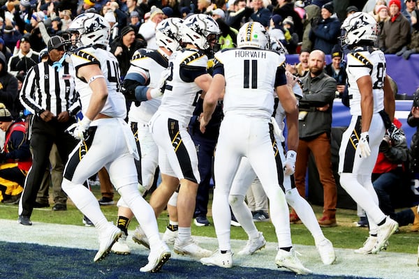 Navy players celebrate after a touchdown during the first half of an NCAA college football game against Army, Saturday, Dec. 14, 2024, in Landover, Md. (AP Photo/Daniel Kucin Jr.)