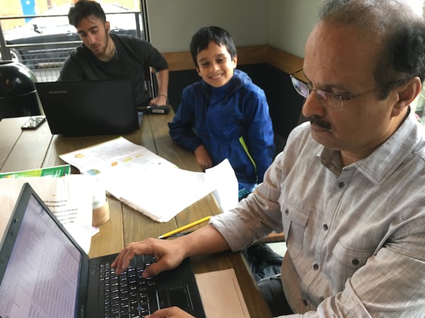 Bala Kandoth (right) with his son Arvin (middle) on Tuesday afternoon at a Starbucks in Marietta. ELLEN ELDRIDGE / ELLEN.ELDRIDGE@AJC.COM