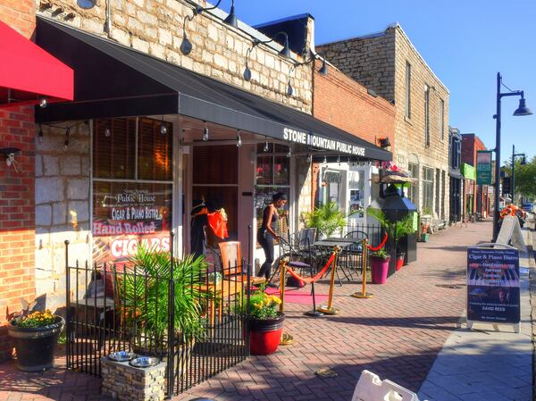 A shopkeeper sets out chairs for patrons at Stone Mountain Public House along Main Street in Stone Mountain Village. (Chris Hunt for The Atlanta Journal-Constitution)