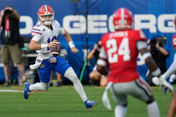 Florida quarterback Aidan Warner, left, scrambles for yardage against Georgia during the first half of an NCAA college football game, Saturday, Nov. 2, 2024, in Jacksonville, Fla. (AP Photo/John Raoux)