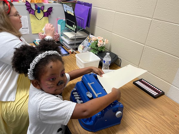 Marlie Langford, a blind kindergartner at J. R. Burrell Elementary School in Marietta, attends a pull-out session to learn Braille and other "incidental" things with visual specialist teacher Tracy Fitch. It was the Friday before Halloween, so Marlie came to school bewhiskered and costumed as a Dalmatian.