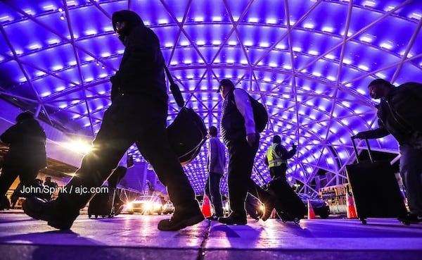 Morning commuters arrive in the cold and under a blue canopy at Hartsfield-Jackson International Airport (ATL) Friday. At midnight, 1800 LED lights on the airport's north canopy will turn blue and burn brightly to commemorate National Human Trafficking Awareness Day. The blue lights will symbolize ATL's  commitment to stamping out sexual exploitation and other forms of human trafficking. JOHN SPINK / JSPINK@AJC.COM