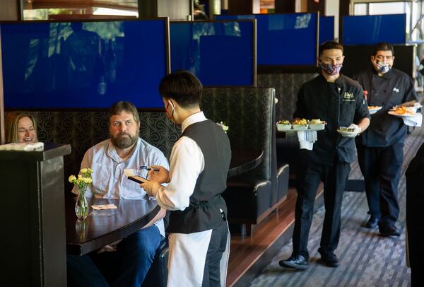 Ray's on the River employees wait on customers at the Sandy Springs location last May. The blue plexiglass shields were constructed to help with customer separation. (STEVE SCHAEFER / SPECIAL TO THE AJC)