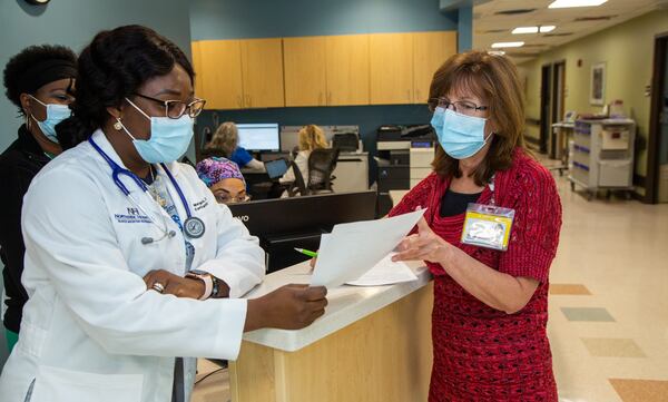 Dr. Margaret O. Apara (left), DNP, talks with social service director Sandi Thurber at a nursing station at Northside Gwinnett Extended Care Center in Lawrenceville. (Phil Skinner for The Atlanta Journal-Constitution)