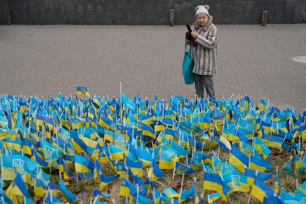 A woman takes a picture at the memorial for those killed during the war in Independence Square in Kyiv, Ukraine, Friday, Feb. 24, 2023. (AP Photo/Thibault Camus)