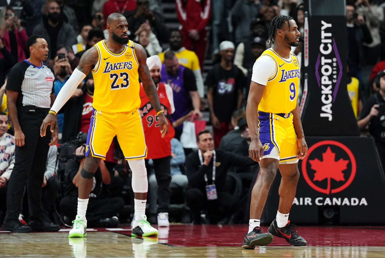 Los Angeles Lakers' LeBron James (23) and Bronny James (9) watch the play during second half of an NBA basketball game against the Toronto Raptors in Toronto on Friday, Nov. 1, 2024. (Frank Gunn/The Canadian Press via AP)