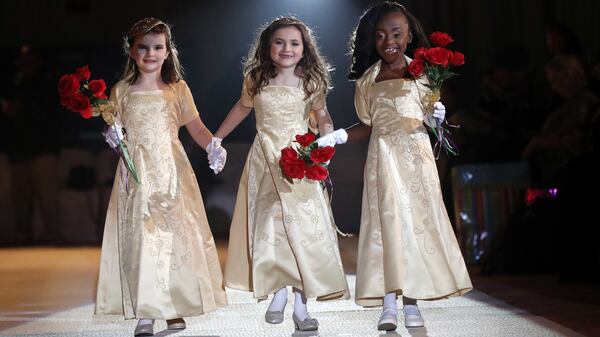 The ladies in waiting of the royal court of the Krewe of Little Rascals walk for the audience during their Mardi Gras Ball in Kenner, La., Thursday, Jan. 25, 2018. The more than 200 kids riding in Sundayâs Mardi Gras parade participated in a glitzy ball held in their honor. (AP Photo/Gerald Herbert)