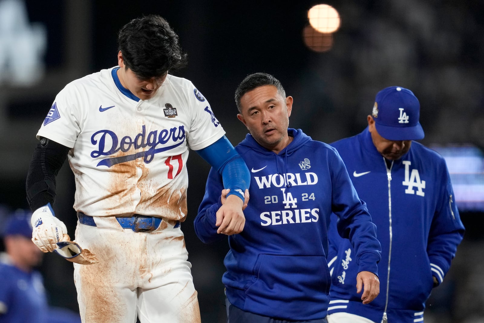 Los Angeles Dodgers' Shohei Ohtani is helped off the field after getting hurt during the seventh inning in Game 2 of the baseball World Series against the New York Yankees, Saturday, Oct. 26, 2024, in Los Angeles. (AP Photo/Ashley Landis)