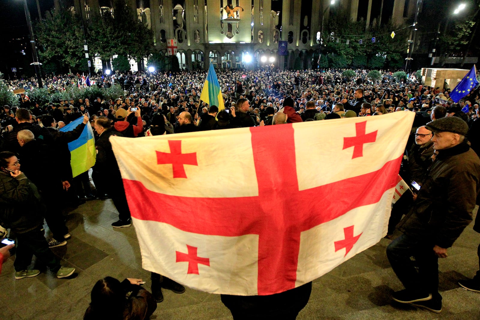 A protester holds Georgian flag during an opposition protest against the results of the parliamentary election in Tbilisi, Georgia, Monday, Oct. 28, 2024. (AP Photo/Shakh Aivazov)