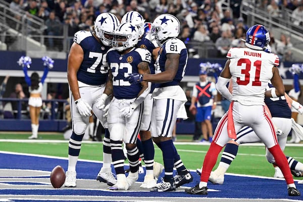 Dallas Cowboys running back Rico Dowdle (23) is surrounded by teammates after scoring a touchdown against the New York Giants during the second half of an NFL football game in Arlington, Texas, Thursday, Nov. 28, 2024. (AP Photo/Jerome Miron)