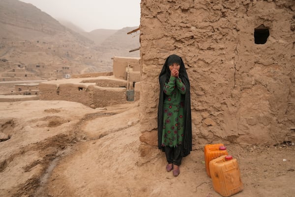 FILE - An Afghan girl warms up her hands as she is resting from carrying the water in Balucha, Afghanistan, Monday, Dec. 14, 2021. (AP Photo/Mstyslav Chernov, File)