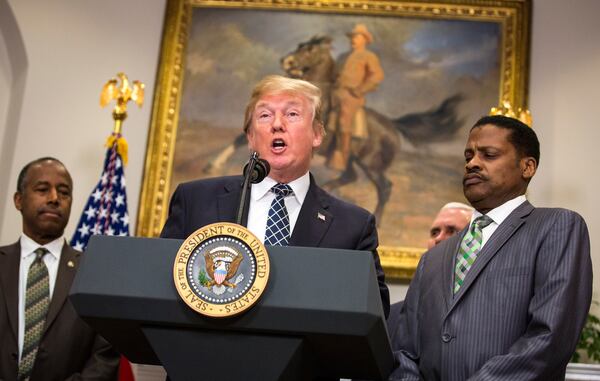 **EDS: PLEASE NOTE POTENTIALLY OBJECTIONABLE CONTENT IN CAPTION.** President Donald Trump speaks as Ben Carson, left, the secretary of Housing and Urban Development, and Isaac Newton Farris Jr., the nephew of Martin Luther King Jr., look on during an event honoring King in the Roosevelt Room of the White House in Washington, Jan. 12, 2018. After the signing, Trump ignored a question from a reporter about whether he is a racist, a day after he reportedly referred to African countries as "shitholes."  (Al Drago/The New York Times)