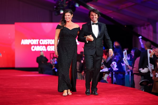 Delta honoree Lindsey Fry Pisli walks down the red carpet with her husband Genti Pisli during the 2024 Delta Chairman’s Club Gala at the Delta Flight Museum on Nov. 21 in Atlanta.  (Jason Getz/AJC)
