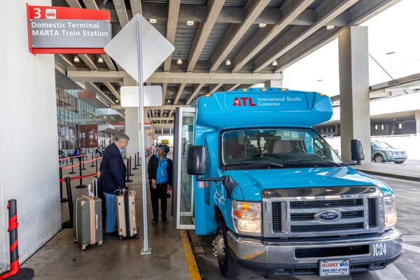 Terminal-to-terminal shuttle driver Anita Jones-Yancey helps a passenger with his luggage at the international terminal Tuesday, Sept. 29, 2023.  (Steve Schaefer/steve.schaefer@ajc.com)