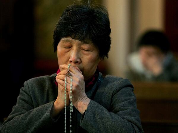 FILE- A woman prays for the health of Pope John Paul II at a state-approved Catholic church in Beijing Saturday April 2, 2005. (AP Photo/Greg Baker, FILE)