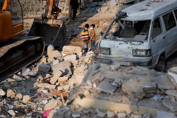 Two boys observe the site where an Israeli airstrike hit a house in Aalmat village, northern Lebanon, Sunday, Nov. 10, 2024. (AP Photo/Hassan Ammar)