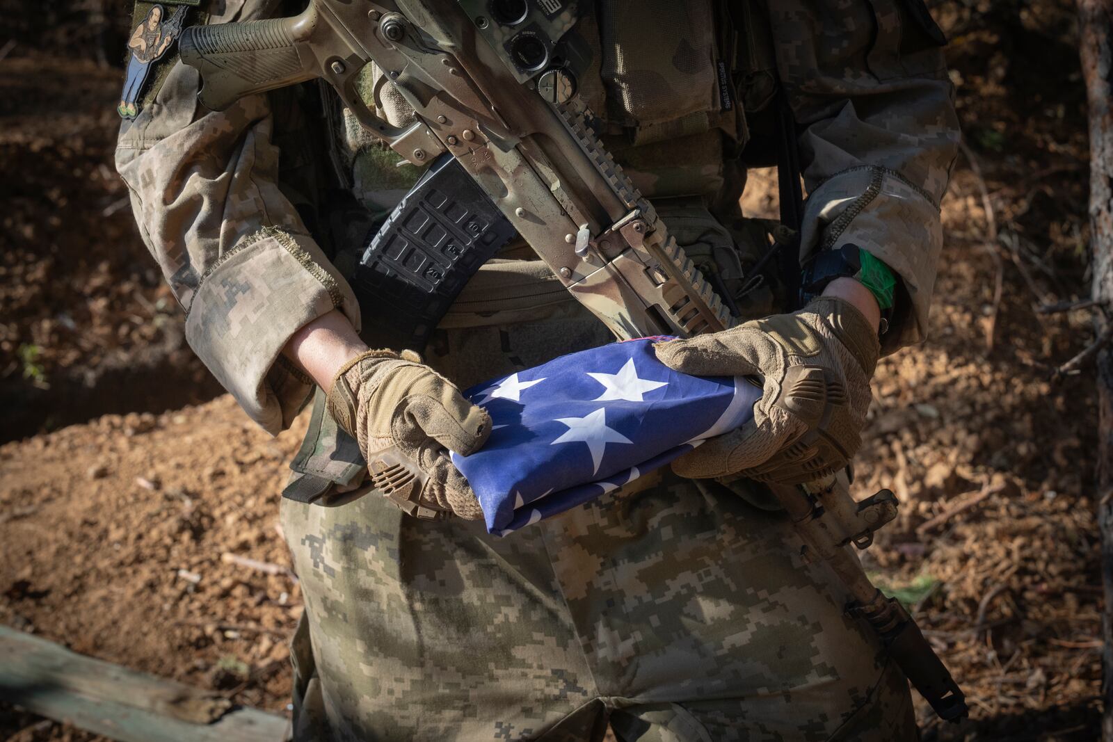 A 25-year-old volunteer fighter with callsign Dima from Texas, who serves with the 23rd separate rifle battalion of Ukraine's Armed Forces, holds the U.S. flag that he always carry with him at the front line in the Kharkiv region, Ukraine, Saturday, Oct. 26, 2024. (AP Photo/Efrem Lukatsky)