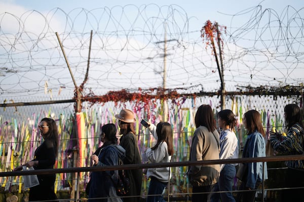 Visitors walk near a wire fence decorated with ribbons written with messages wishing for the reunification of the two Koreas at the Imjingak Pavilion in Paju, South Korea, Thursday, Oct. 31, 2024. (AP Photo/Lee Jin-man)