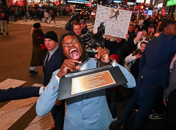 Travis Hunter poses in Times Square with the Heisman Trophy after winning it as the outstanding player in college football Saturday, Dec. 14, 2024, in New York. (Todd Van Emst/Heisman Trust via AP, Pool)