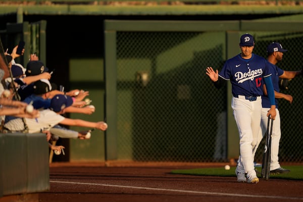 Los Angeles Dodgers designated hitter Shohei Ohtani waves to fans as he enters the field before a spring training baseball game against the Los Angeles Angels, Friday, Feb. 28, 2025, in Phoenix. (AP Photo/Ashley Landis)