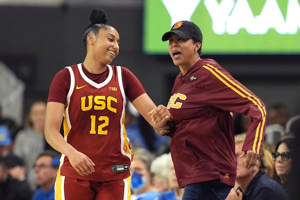 Southern California guard JuJu Watkins, left, reacts to getting a slap on the behind from former USC player Cheryl Miller after scoring during the second half of an NCAA college basketball game against UCLA Saturday, March 1, 2025, in Los Angeles. (AP Photo/Mark J. Terrill)