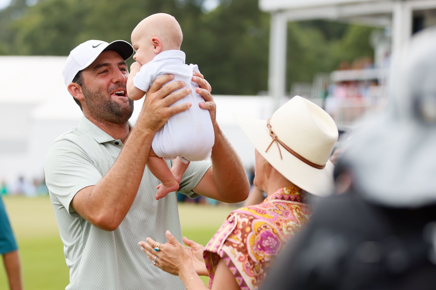 Scottie Scheffler lifts his baby as his wife Meredith looks on after winning the Tour Championship at East Lake Golf Club, Sunday, Sept. 1, 2023, in Atlanta. 
(Miguel Martinez / AJC)