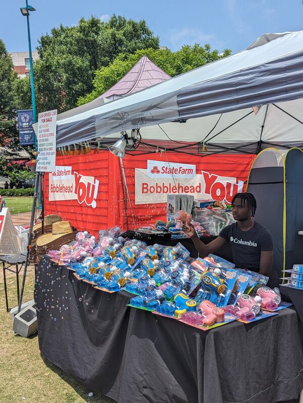 Bubble machines sold next to a tent where State Farm was giving out personalized bobbleheads on Saturday, June 17, 2023, at the Juneteenth Atlanta Parade and Festival at Centennial Olympic Park. Mirtha Donastorg for the AJC