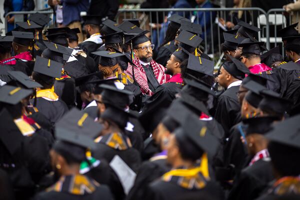 A graduate wears a kaffiyeh and faces away from President Joe Biden in protest of the war in Gaza at the commencement ceremony at Morehouse College in Atlanta on Sunday, May 19, 2024. (Arvin Temkar / AJC)