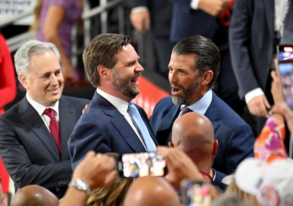 U.S. Sen. JD Vance (center), R-Ohio, and Donald Trump Jr. (right) share a smile as they wait for former President Donald Trump during the Republican National Convention in Milwaukee.