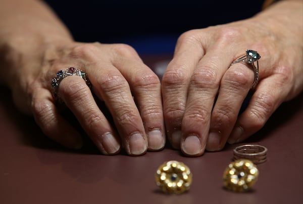 Kathy Kinev wears both award-winning platinum rings and places two more contemporary earrings made for clients at her workshop in Atlanta recently. HENRY TAYLOR / HENRY.TAYLOR@AJC.COM