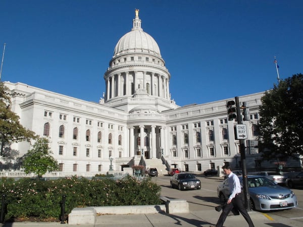 FILE - A man walks by the Wisconsin Capitol, Oct. 10, 2012, in Madison, Wis. (AP Photo/Scott Bauer, File)