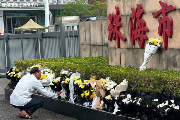 A man offers flowers outside the "Zhuhai People's Fitness Plaza" where a man rammed his car into people exercising at the sports center, in Zhuhai in southern China's Guangdong province on Wednesday, Nov. 13, 2024. (AP Photo/Ng Han Guan)