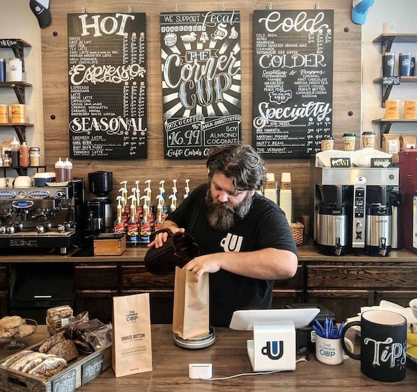 Justin Finegan, seen filling a bag of coffee beans for sale, lives near the Decatur store and is amazed at how many of his neighbors he’s gotten to know through the Corner Cup. CONTRIBUTED BY RICH LAVERY