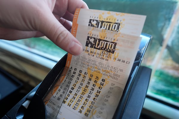 Edith Patlan grabs printed tickets from a Texas Lottery sales terminal at Fuel City in Dallas, Wednesday, Feb. 26, 2025. (AP Photo/LM Otero)