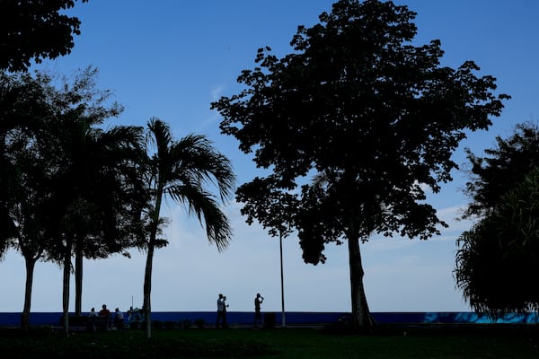 Migrants from Afghanistan and Russia, who were deported from the U.S., walk along the waterfront in Panama City, Tuesday, March 18, 2025, after visiting the Canadian Embassy in hopes of applying for asylum. (AP Photo/Matias Delacroix)